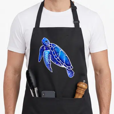 Tablier de cuisine noir avec une tortue de mer stylisée en nuances de bleu et de blanc.