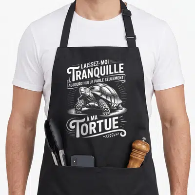 Tablier de cuisine noir avec une tortue gravée et le texte Laissez-moi tranquille à ma tortue en blanc.