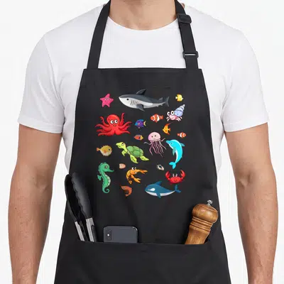 Tablier de cuisine noir avec un poisson clown, un octopus rouge, un shark et divers animaux marins colorés et mignons imprimés au centre.