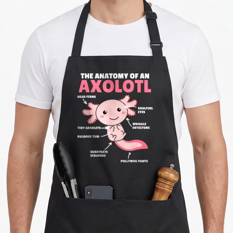 Tablier de cuisine noir avec illustration colorée d'un axolotl rose et ses annotations anatomiques fantaisistes.