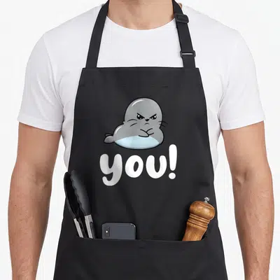 Tablier de cuisine noir avec un phoque gris aux bras croisés et le texte Phoque You en blanc.