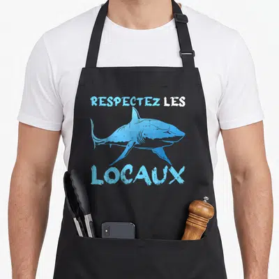 Tablier de cuisine noir avec illustration de requin bleu et texte Respectez les Locaux imprimé en typographie délavée.