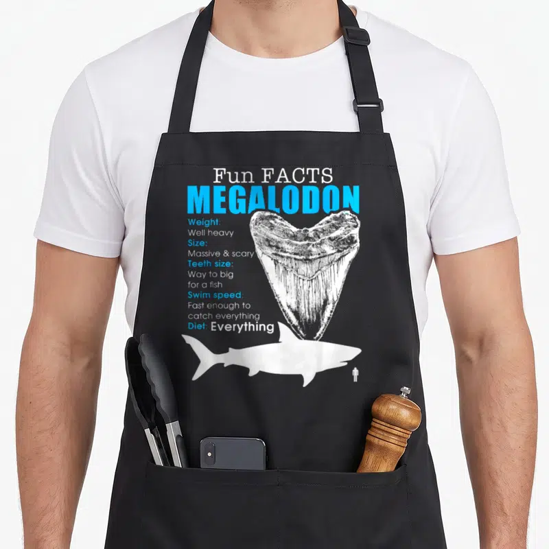 Tablier de cuisine noir avec illustration d'une dent de Mégalodon et texte blanc et bleu.