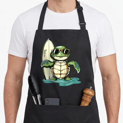 Tablier de cuisine noir avec une tortue de mer surfeuse portant des lunettes noires et tenant une planche de surf.
