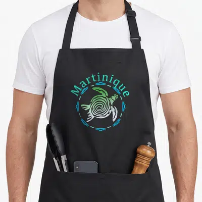 Tablier de cuisine noir avec une tortue tribale verte et l'inscription Martinique en arc de cercle turquoise.