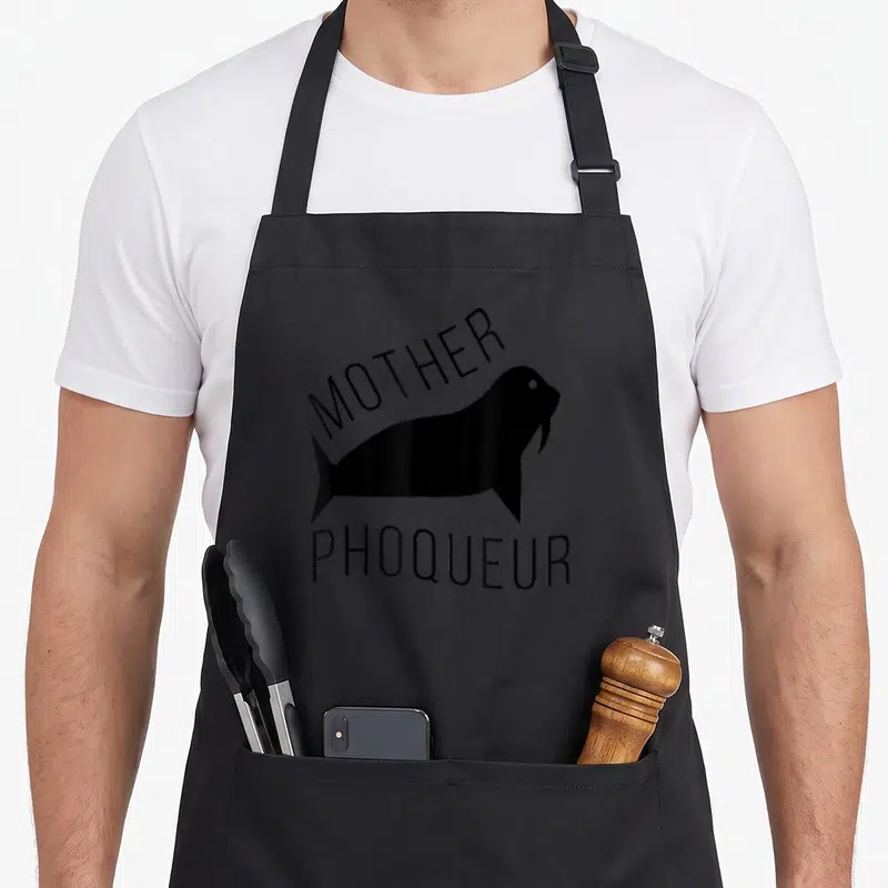 Tablier de cuisine noir avec silhouette de phoque et texte Mother Phoqueur imprimé en noir.