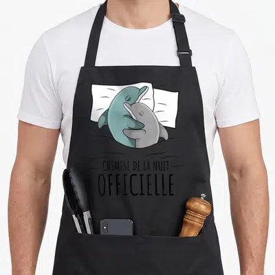 Tablier de cuisine noir avec deux dauphins s'enlaçant sur un oreiller et le texte « chemise de la nuit ».