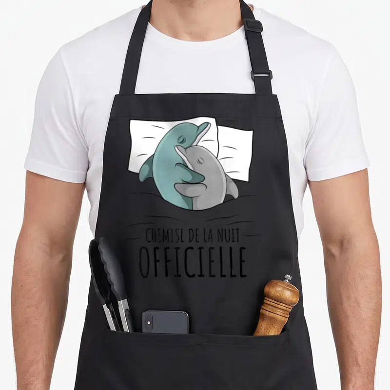 Tablier de cuisine noir avec deux dauphins s'enlaçant sur un oreiller et le texte « chemise de la nuit ».