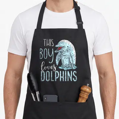 Tablier de cuisine noir avec illustration vintage d'un dauphin bleu et texte This Boy Loves Dolphins en blanc et bleu clair.