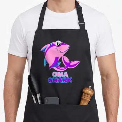 Tablier de cuisine noir avec un requin rose et violet et le texte Oma Shark imprimé en bas.