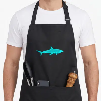 Tablier de cuisine noir avec une silhouette de shark turquoise stylisée en pointillés sur le devant.