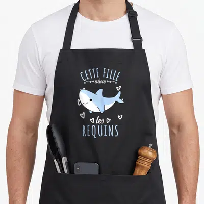 Tablier de cuisine noir avec requin bleu mignon et texte Cette Fille Aime les Requins entouré de petits cœurs blancs.