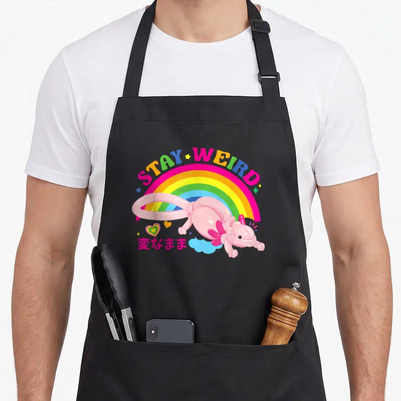 Tablier de cuisine noir avec un axolotl ballon rose, un arc-en-ciel et le texte Stay Weird multicolore.