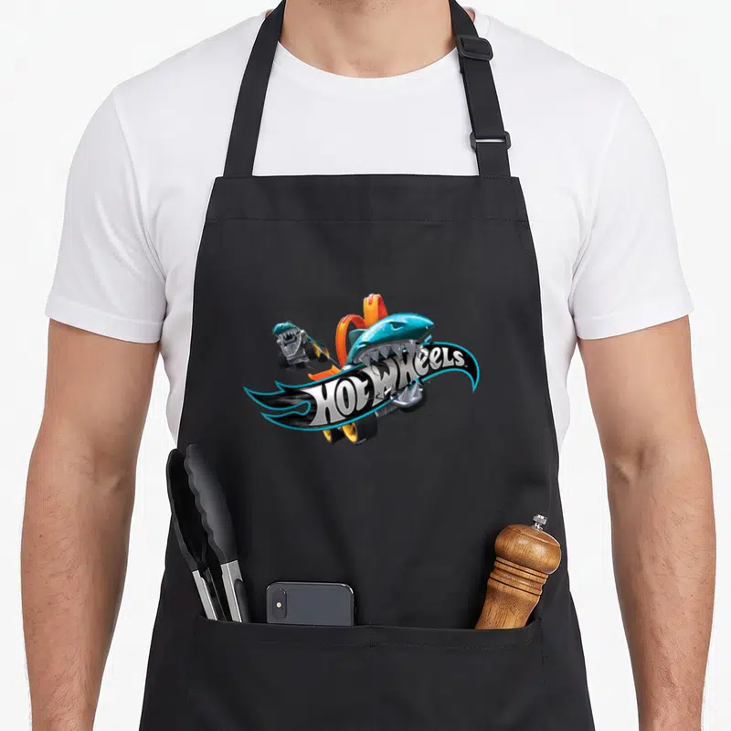Tablier de cuisine noir avec un requin turquoise mordant le logo Hot Wheels en flammes bleues et noires.
