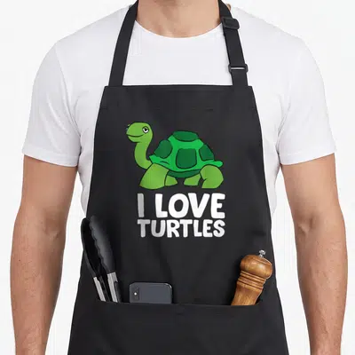 Tablier de cuisine noir avec une tortue verte stylisée et le texte blanc I LOVE TURTLES imprimé au centre.
