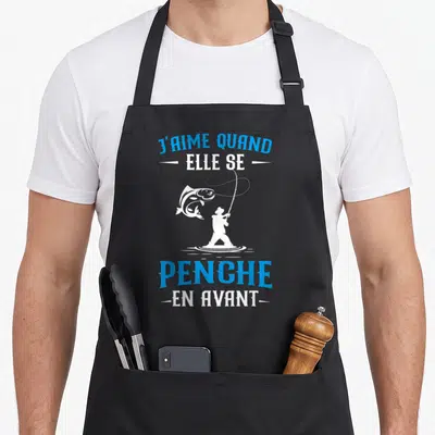 Tablier de cuisine noir avec silhouette blanche de pêcheur et texte bleu J'aime quand elle se penche en avant