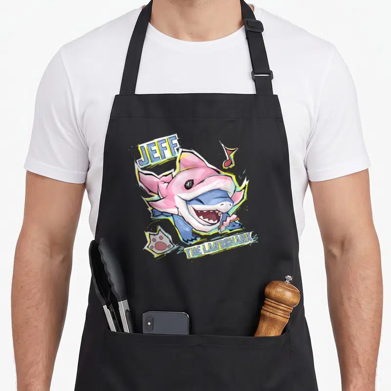 Tablier de cuisine noir avec illustration colorée d'un requin portant un déguisement de dauphin rose.
