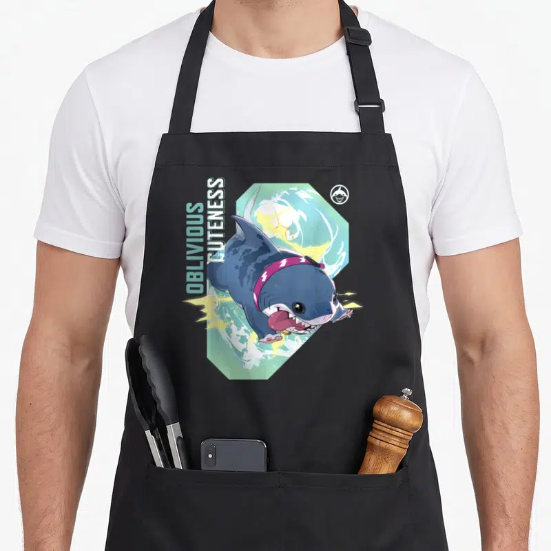 Tablier de cuisine noir avec un requin bleu stylisé et le texte Oblivious Cuteness imprimé verticalement.