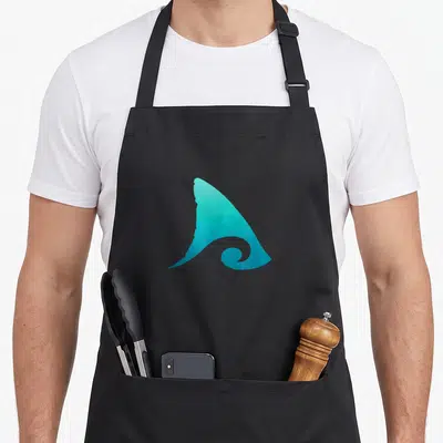 Tablier de cuisine noir avec une illustration stylisée d'une aile de requin teck émergeant d'une vague.