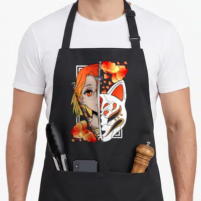Tablier de cuisine noir avec illustration d'une fille samouraï aux cheveux orange, tenant une épée devant un masque blanc et des fleurs rouges.