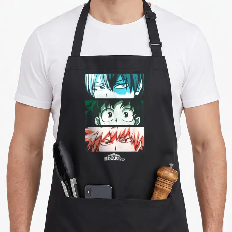 Tablier de cuisine noir avec trois portraits d'anciens herois anime et le titre du manga en japonais.