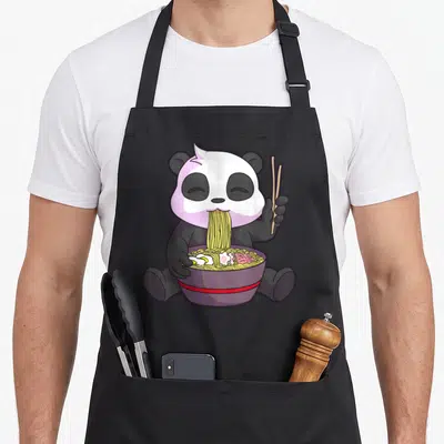 Tablier de cuisine noir avec illustration d'un panda kawaii mangeant du ramen avec des baguettes dans un bol violet.