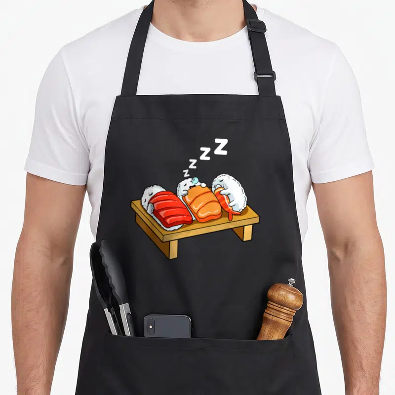 Tablier de cuisine noir avec trois sushis cartoon endormis et des Z en blanc.