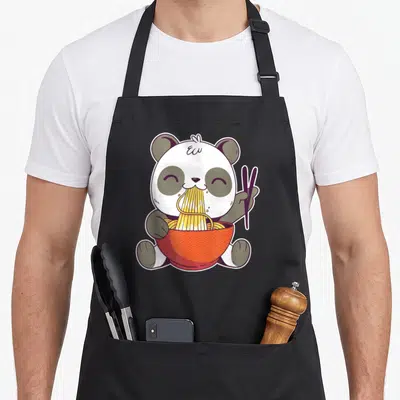 Tablier de cuisine noir avec illustration d'un panda kawaii mangeant des ramen dans un bol rouge orné de motifs.