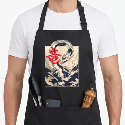 Tablier de cuisine noir avec illustration dragon et kanji rouge sur fond crème et vagues bleues.