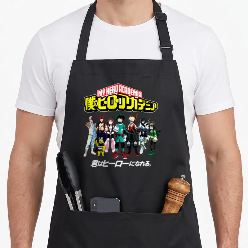 Tablier de cuisine noir avec illustration du groupe Class 1A et lettrages japonais stylisés en jaune et rouge.