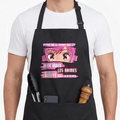 Tablier de cuisine noir avec illustration d'yeux manga roses et texte humoristique sur les jeux vidéo et les animes.