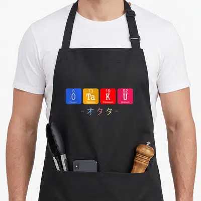 Tablier de cuisine noir avec quatre cases colorées du tableau périodique et des caractères kanjis en dessous.