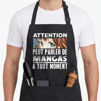 Tablier de cuisine noir avec une illustration d'yeux anime et le texte blanc Attention peut parler de mangas à tout moment