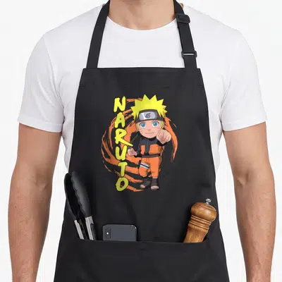 Tablier de cuisine noir avec illustration Naruto chibi pointant le doigt et texte NARUTO vertical jaune sur swirl orange