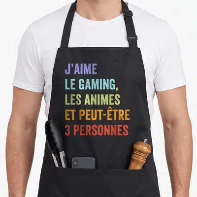 Tablier de cuisine noir avec texte multicolore J'aime le gaming les animes et peut-être 3 personnes imprimé au centre du torse.