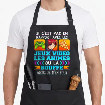 Tablier de cuisine noir avec une illustration de fille aux cheveux roses, manette verte et pizza sous un slogan humoristique sur les passions.