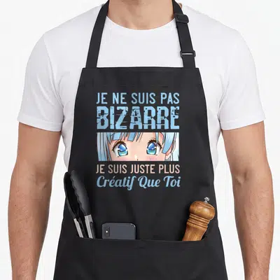 Tablier de cuisine noir avec illustration manga aux yeux bleus et texte Je ne suis pas bizarre je suis juste plus créatif que toi