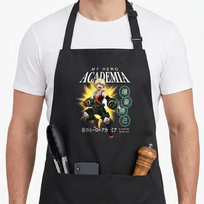 Tablier de cuisine noir avec l'illustration colorée de Katsuki Bakugo et le titre My Hero Academia en lettres blanches.