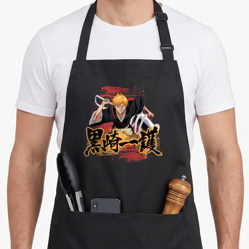 Tablier de cuisine noir avec illustration d'Ichigo brandissant son sabre et ses kanjis orange.