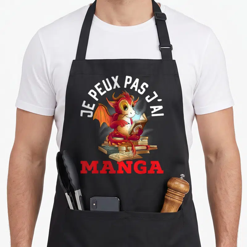 Tablier de cuisine noir avec un dragon rouge lisant des livres et le texte Je peux pas j'ai manga en haut.