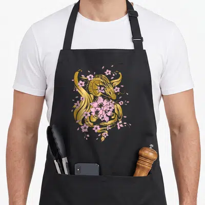 Tablier de cuisine noir avec un dragon doré et des fleurs de cerisier sakura roses imprimés au centre.