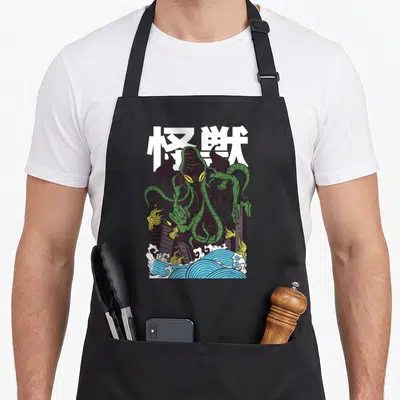 Tablier de cuisine noir avec illustration d'un monstre vert tentaculaire sur fond de kanjis blancs et d'ondes bleues stylisées.
