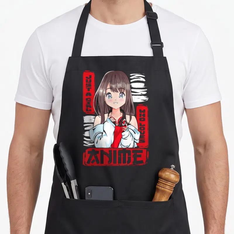 Tablier de cuisine noir avec une fille anime aux cheveux brons et casque rouge entourée de texte graffiti rouge.