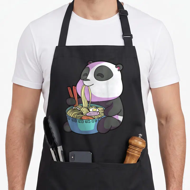 Tablier de cuisine noir avec illustration d'un panda kawaii mangeant un bol de ramen avec des baguettes roses.