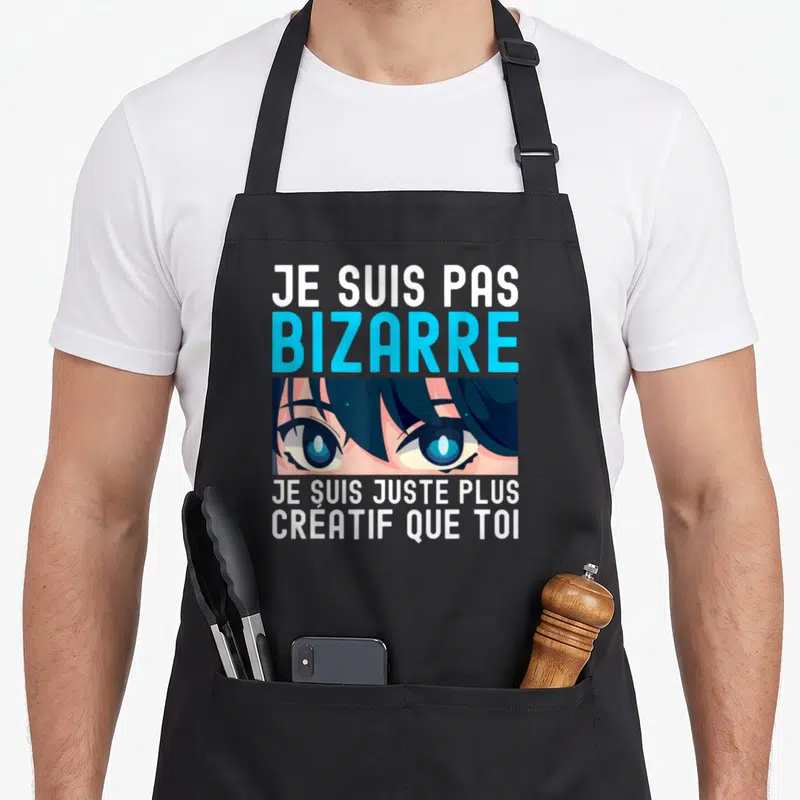 Tablier de cuisine noir avec une illustration de yeux anime bleus et le texte Je suis pas bizarre je suis juste plus créatif que toi.