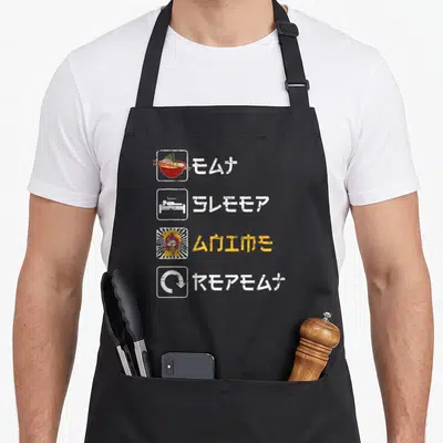 Tablier de cuisine noir avec illustration bol de ramen, personnage kawaii et symboles graphiques style manga japonais.