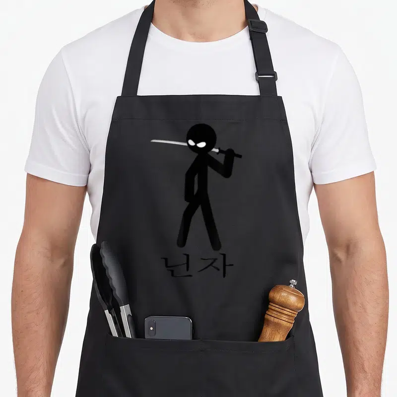 Tablier de cuisine noir avec ninja stick figure noir tenant une katana blanche au-dessus de l'épaule et des caractères en dessous.