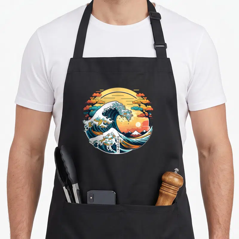 Tablier de cuisine noir avec une illustration circulaire d'un tsunami stylisé Manga et du Mont Fuji au fond.
