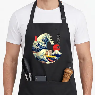 Tablier de cuisine noir avec illustration d'un bulldog surfant sur une onde style ukiyo-e et du Mont Fuji en arrière-plan.