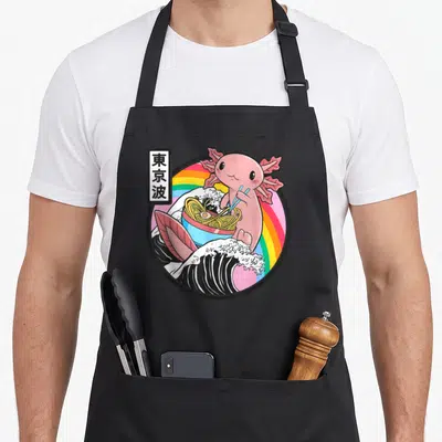 Tablier de cuisine noir avec illustration d'un axolotl rose mangeant des ramen au-dessus d'une vague style Kanagawa et d'un arc-en-ciel.